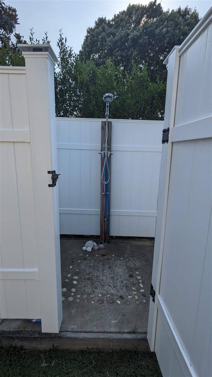 Outdoor shower plumbing and pebble drainage pad built by Evoke Design + Build in Cape Charles, VA