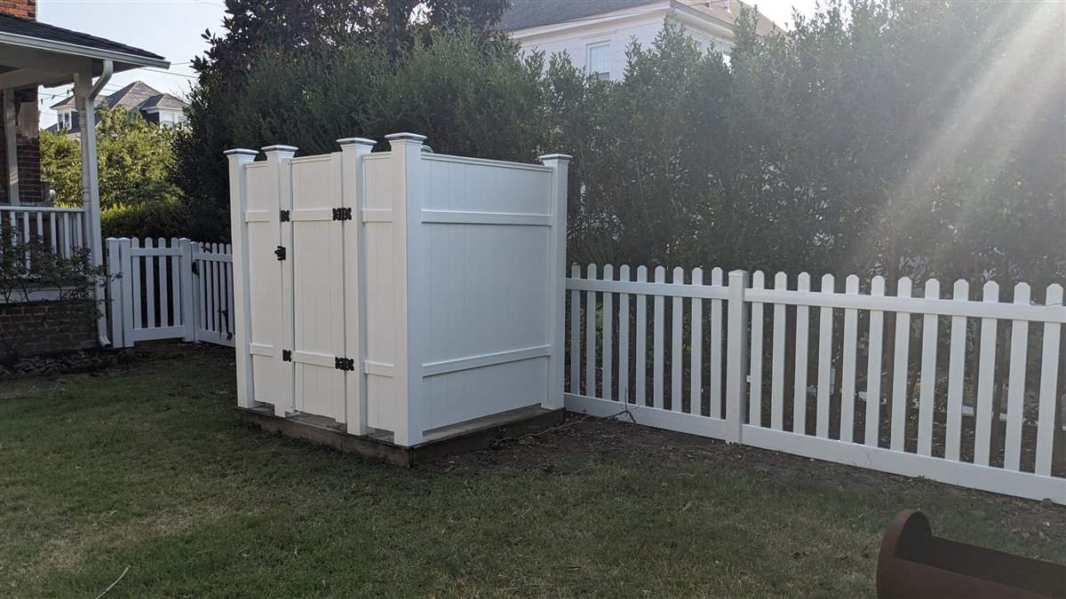 Vinyl outdoor shower enclosure integrated with picket fence, built by Evoke Design + Build in Cape Charles, VA